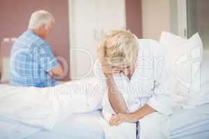 Tensed senior couple sitting in bedroom