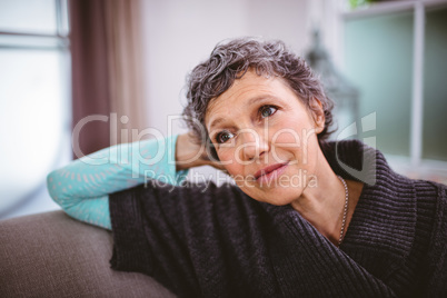 Thoughtful mature woman sitting on sofa