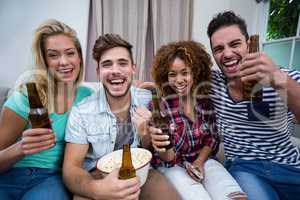Cheerful friends enjoying beer while watching match at home