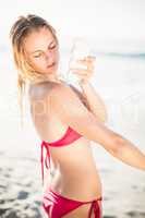 Woman applying sunscreen lotion on the beach
