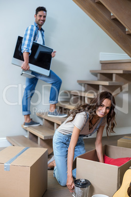 Smiling man holding computer with woman unpacking objects