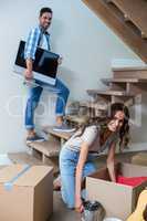 Smiling man holding computer with woman unpacking objects