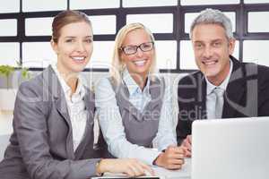 Happy business people with laptop at desk