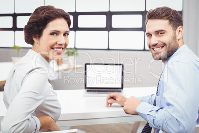 Happy business people sitting at laptop desk