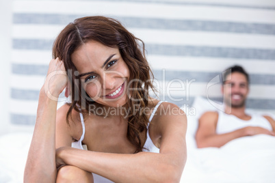 Woman smiling while husband lying on bed in background