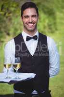 Handsome waiter holding a tray with two glasses of wine