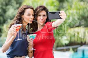 Happy friends taking self portrait while holding drinks