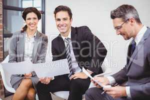 Cheerful business professionals holding documents while sitting