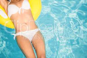 Mid section of a woman in white bikini floating on inflatable tu