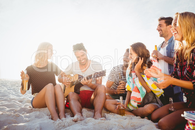 Happy friends having fun while sitting on sand