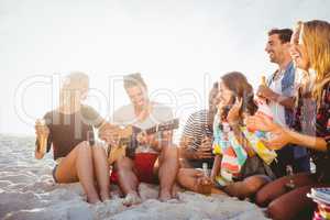 Happy friends having fun while sitting on sand