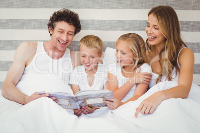 Happy family reading book on bed
