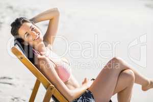 Happy woman sitting on an armchair on the beach