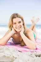 Portrait of happy woman in bikini lying on the beach