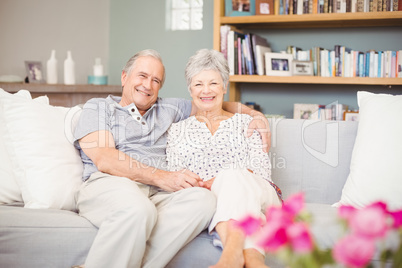 Portrait of smiling senior couple sitting on sofa in living room