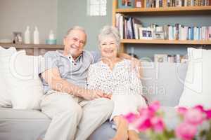 Portrait of smiling senior couple sitting on sofa in living room