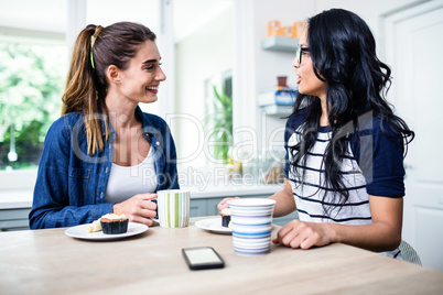 Young female friends talking while having breakfast