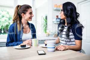 Young female friends talking while having breakfast