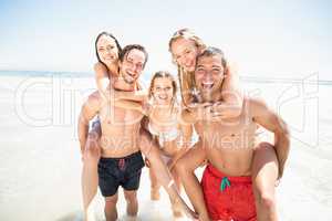 Men giving a piggy back to women on the beach