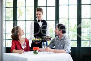 Waitress serving meal to a couple