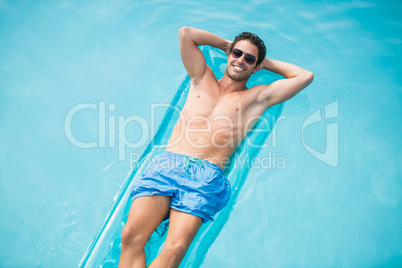 Shirtless man relaxing on inflatable raft