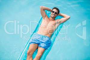Shirtless man relaxing on inflatable raft