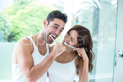 Young couple smiling while brushing teeth