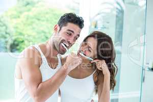 Young couple smiling while brushing teeth