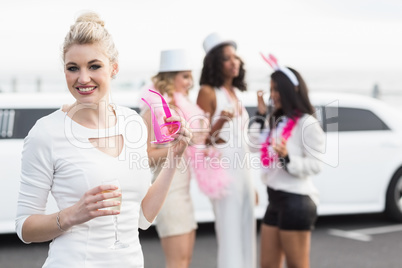 Frivolous women drinking champagne next to a limousine