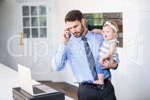 Businessman looking in laptop while carrying daughter