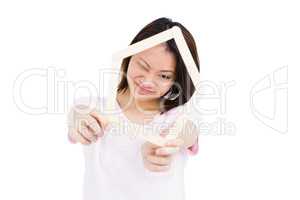 Young woman holding house shaped popsicle sticks on face