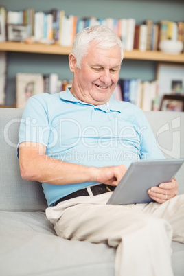 Smiling senior man using digital tablet