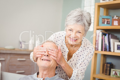 Portrait of senior woman hiding eyes of her husband