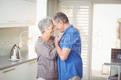 Happy senior couple romancing in kitchen