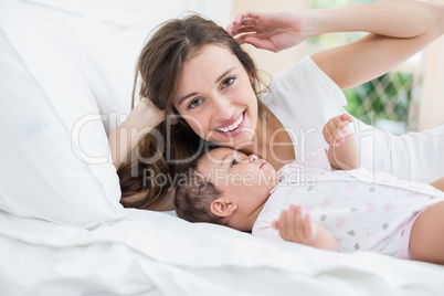 Smiling woman lying with baby on bed