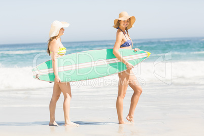 Two women carrying surfboard on the beach