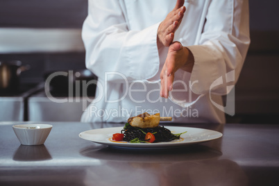 Chef sprinkling spices on dish