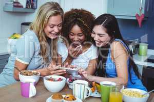 Smiling female friends using mobile phone