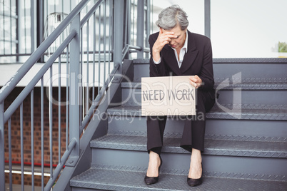 Unemployed businesswoman holding need work placard