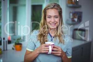 Young woman drinking coffee while standing in kitchen