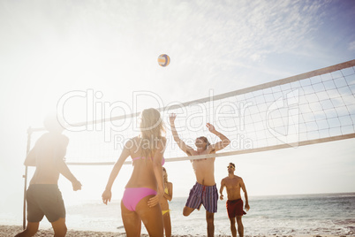 Happy friends playing beach volleyball