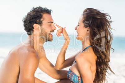 Happy girlfriend putting suncream on boyfriend