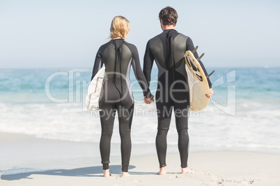 Rear view of couple holding hands on the beach
