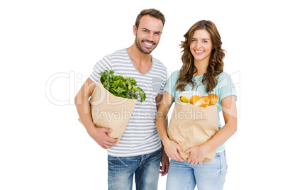 Happy young couple holding bag of vegetables