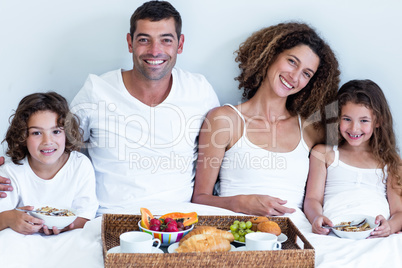 Portrait of a family sitting with breakfast tray in bed