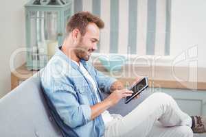 Man smiling while using digital tablet on sofa