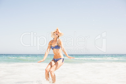 Happy woman in bikini and hat having fun on the beach