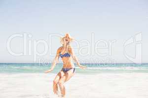 Happy woman in bikini and hat having fun on the beach