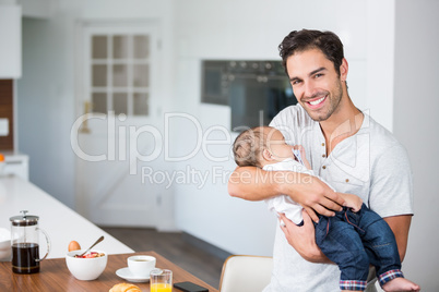Portrait of happy father carrying baby