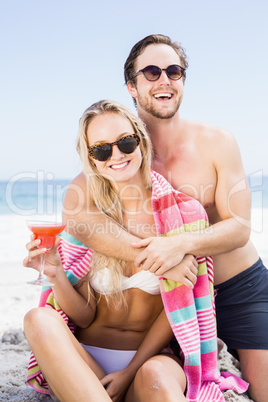 Young couple in sunglasses embracing on the beach